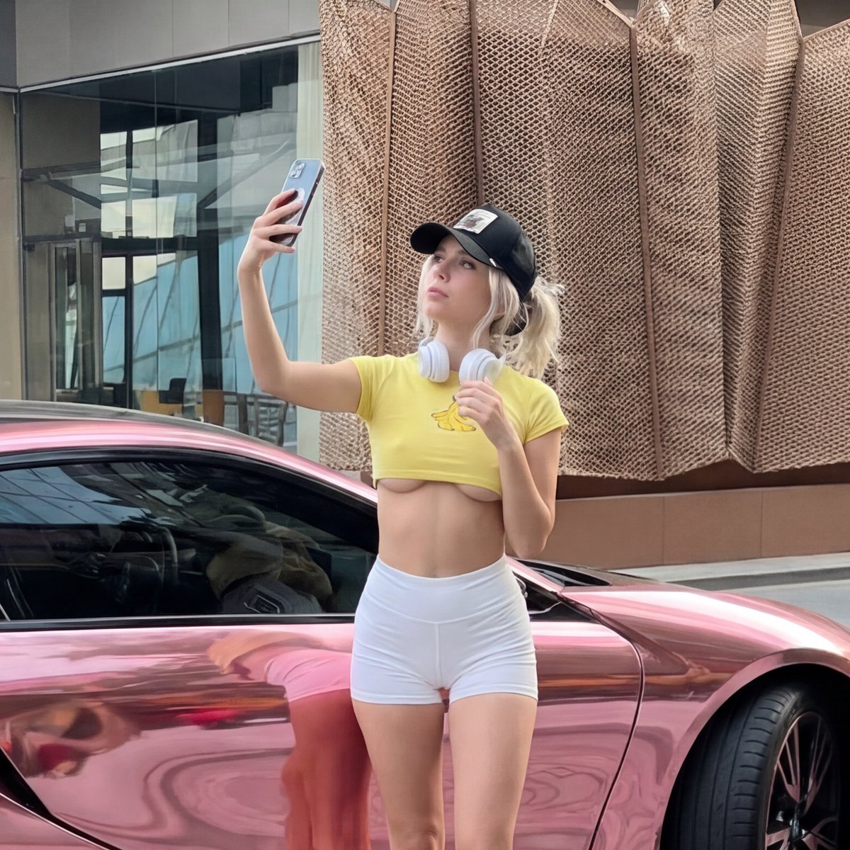 Young woman taking selfie next to chrome pink BMW i8